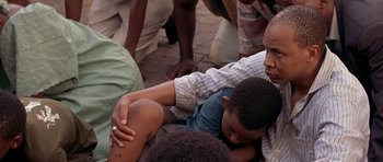 Movie still from “Hotel Rwanda” (2004), directed by Terry George – A group of people gathered around a man holding a child; Close Up shot, Over the shoulder angle