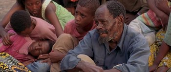 Movie still from “Hotel Rwanda” (2004), directed by Terry George – A man sitting next to a boy in a crowd; Close Up shot, High angle