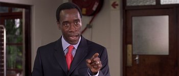 Movie still from “Hotel Rwanda” (2004), directed by Terry George – A man wearing a suit and red neck tie; Close Up shot, Over the shoulder angle