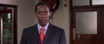 Movie still from “Hotel Rwanda” (2004), directed by Terry George – A man wearing a suit and tie standing in front of a wall; Close Up shot, Low angle