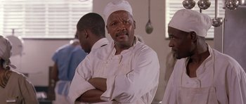 Movie still from “Hotel Rwanda” (2004), directed by Terry George – A man in a chef's outfit is posing for a picture; Close Up shot, Low angle