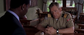 Movie still from “Hotel Rwanda” (2004), directed by Terry George – A man sitting at a table with another man in front of him; Close Up shot, Over the shoulder angle