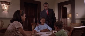Movie still from “Hotel Rwanda” (2004), directed by Terry George – A group of people sitting at a table with papers; Medium shot, Over the shoulder angle