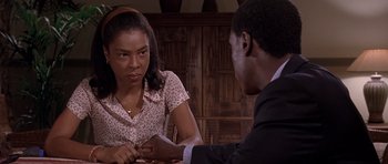 Movie still from “Hotel Rwanda” (2004), directed by Terry George – A woman sitting at a table talking to a man in a suit; Close Up shot, Over the shoulder angle