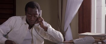 Movie still from “Hotel Rwanda” (2004), directed by Terry George – A man talking on a phone while sitting down; Close Up shot, High angle