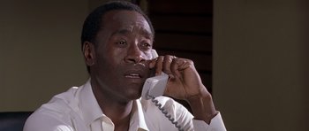 Movie still from “Hotel Rwanda” (2004), directed by Terry George – A man talking on a phone while wearing a white shirt; Close Up shot, Low angle