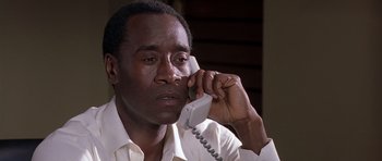Movie still from “Hotel Rwanda” (2004), directed by Terry George – A black man talking on a phone while wearing a white dress shirt; Close Up shot, Low angle