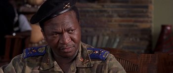 Movie still from “Hotel Rwanda” (2004), directed by Terry George – A man in a military uniform sitting in a chair; Close Up shot, Low angle