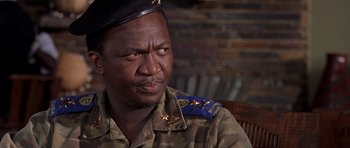 Movie still from “Hotel Rwanda” (2004), directed by Terry George – A man in a military uniform is sitting in a chair; Close Up shot, Low angle