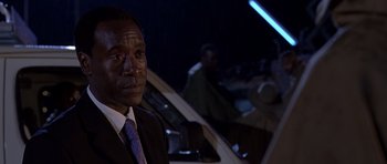 Movie still from “Hotel Rwanda” (2004), directed by Terry George – A man wearing a suit and tie standing next to a car; Close Up shot, Over the shoulder angle