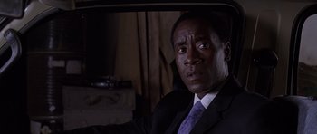 Movie still from “Hotel Rwanda” (2004), directed by Terry George – A man wearing a suit and tie sitting in a car; Close Up shot, Low angle