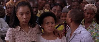 Movie still from “Hotel Rwanda” (2004), directed by Terry George – A group of people standing around each other in a room; Close Up shot, Over the shoulder angle