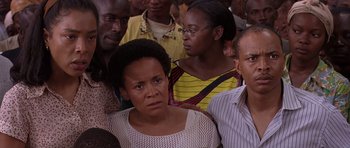 Movie still from “Hotel Rwanda” (2004), directed by Terry George – A group of people standing around each other in a room; Close Up shot, High angle