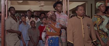 Movie still from “Hotel Rwanda” (2004), directed by Terry George – A group of people standing in a room; Medium shot, Low angle