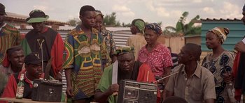 Movie still from “Hotel Rwanda” (2004), directed by Terry George – A group of people standing around a man holding a radio; Medium shot, Low angle