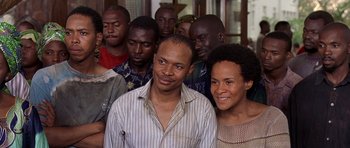 Movie still from “Hotel Rwanda” (2004), directed by Terry George – A group of people that are standing in a room together; Close Up shot, High angle
