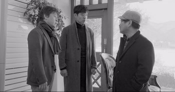 Three men standing next to each other in front of a window