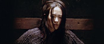 Movie still from “House of Flying Daggers” (2004), directed by Yimou Zhang – A woman with long black hair sitting on top of a wooden bench; Close Up shot, High angle
