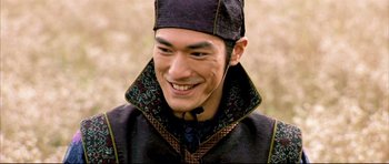 Movie still from “House of Flying Daggers” (2004), directed by Yimou Zhang – A man wearing a hat smiling for the camera; Close Up shot, Over the shoulder angle