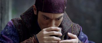 Movie still from “House of Flying Daggers” (2004), directed by Yimou Zhang – A man holding a coffee mug while looking down; Close Up shot, High angle