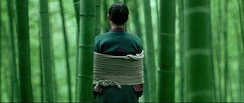 Movie still from “House of Flying Daggers” (2004), directed by Yimou Zhang – A woman tied up with a rope in a bamboo forest; Medium shot, Low angle