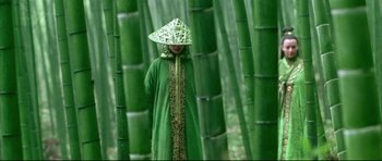 Movie still from “House of Flying Daggers” (2004), directed by Yimou Zhang – A person wearing a hat standing in the middle of a bamboo forest; Wide shot, High angle