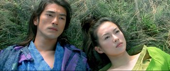 Movie still from “House of Flying Daggers” (2004), directed by Yimou Zhang – A man and a woman laying in the grass; Close Up shot, Overhead angle