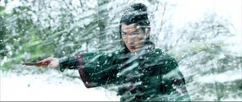 Movie still from “House of Flying Daggers” (2004), directed by Yimou Zhang – A man in a green jacket is standing in the snow; Medium shot, Over the shoulder angle