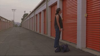 Movie still from “House of Sand and Fog” (2003), directed by Vadim Perelman – A man standing in front of a row of storage units; Wide shot, Low angle