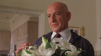Movie still from “House of Sand and Fog” (2003), directed by Vadim Perelman – A man in a suit holding a bouquet of white flowers; Close Up shot, Low angle