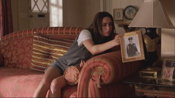 Movie still from “House of Sand and Fog” (2003), directed by Vadim Perelman – A woman sitting on top of a couch looking at an old picture; Medium shot, Over the shoulder angle