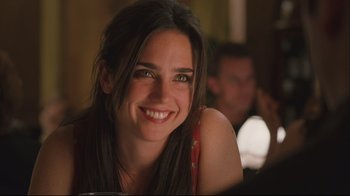 Movie still from “House of Sand and Fog” (2003), directed by Vadim Perelman – A woman smiling for the camera while sitting at a table; Close Up shot, Over the shoulder angle