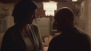 Movie still from “House of Sand and Fog” (2003), directed by Vadim Perelman – A woman standing next to a man in a room; Close Up shot, Over the shoulder angle