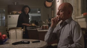 Movie still from “House of Sand and Fog” (2003), directed by Vadim Perelman – A man sitting at a table in front of a woman in a kitchen; Medium shot, Over the shoulder angle