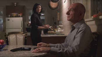 Movie still from “House of Sand and Fog” (2003), directed by Vadim Perelman – An older man sitting at a counter in front of a woman in a kitchen; Medium shot, Over the shoulder angle