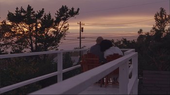 Movie still from “House of Sand and Fog” (2003), directed by Vadim Perelman – A man and a woman sitting on a chair on a deck; Wide shot, Low angle