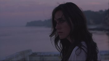Movie still from “House of Sand and Fog” (2003), directed by Vadim Perelman – A woman with long black hair standing next to a body of water; Close Up shot, Low angle