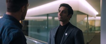 Movie still from “Venom” (2018), directed by Ruben Fleischer – A man in a suit standing next to a glass wall; Close Up shot, Over the shoulder angle