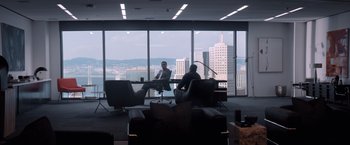 Movie still from “Venom” (2018), directed by Ruben Fleischer – Two men sitting at a table in front of a large window; Wide shot, Over the shoulder angle