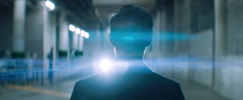 Movie still from “Venom” (2018), directed by Ruben Fleischer – A man is seen from behind with a light shining on his face; Medium shot, Low angle