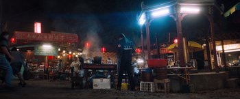 Movie still from “Venom” (2018), directed by Ruben Fleischer – A man standing in front of an open air market; Wide shot, Over the shoulder angle