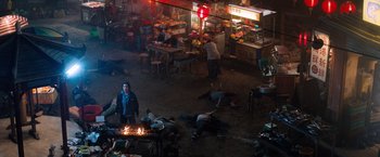 Movie still from “Venom” (2018), directed by Ruben Fleischer – A group of people laying on the ground next to a fire pit; Extreme Wide shot, High angle