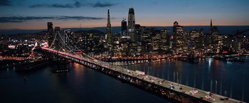 Movie still from “Venom” (2018), directed by Ruben Fleischer – An aerial view of a city at night with a bridge; Extreme Wide shot, High angle
