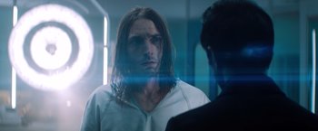 Movie still from “Venom” (2018), directed by Ruben Fleischer – A man with long brown hair is looking at another man; Close Up shot, Over the shoulder angle