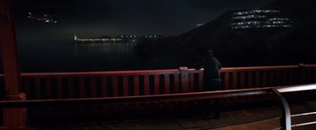 Movie still from “Venom” (2018), directed by Ruben Fleischer – A man sitting on a bench looking at a body of water at night; Extreme Wide shot, High angle