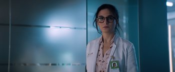 Movie still from “Venom” (2018), directed by Ruben Fleischer – A woman wearing a white lab coat and glasses in a room; Close Up shot, Low angle