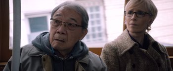 Movie still from “Venom” (2018), directed by Ruben Fleischer – An older man wearing glasses and a jacket; Close Up shot, Over the shoulder angle