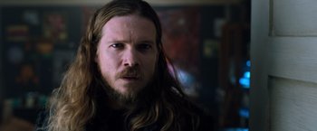 Movie still from “Venom” (2018), directed by Ruben Fleischer – A person with long hair and a beard; Close Up shot, Low angle