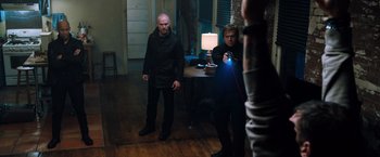 Movie still from “Venom” (2018), directed by Ruben Fleischer – Two men standing in a living room with a lamp; Wide shot, Low angle