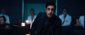 Movie still from “Venom” (2018), directed by Ruben Fleischer – A man in a black jacket sitting in front of a wall; Medium shot, Over the shoulder angle